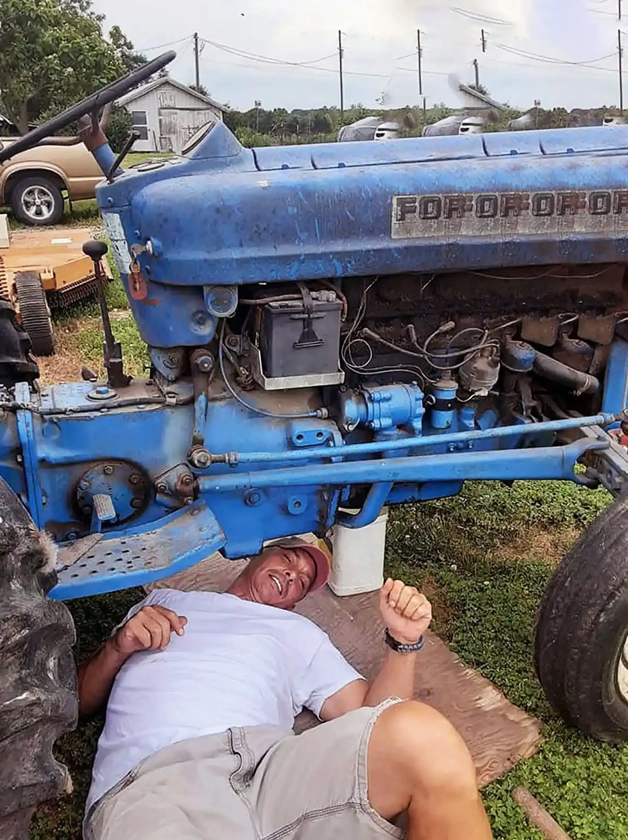 The blue tractor for his book Spring Break to Mars book, author David Haave gives it an oil change; Tipton, MO, USA. -- David Haave